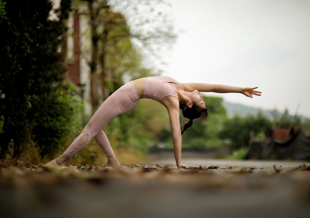 class-02 Woman practicing yoga outdoors on a forest road, emphasizing fitness and balance.