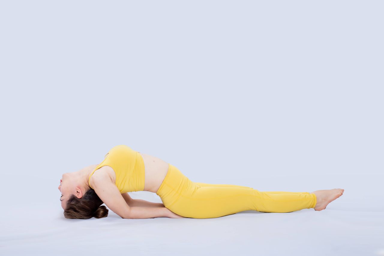 journey-img Adult woman in a yellow yoga outfit practicing bridge pose on a studio floor.