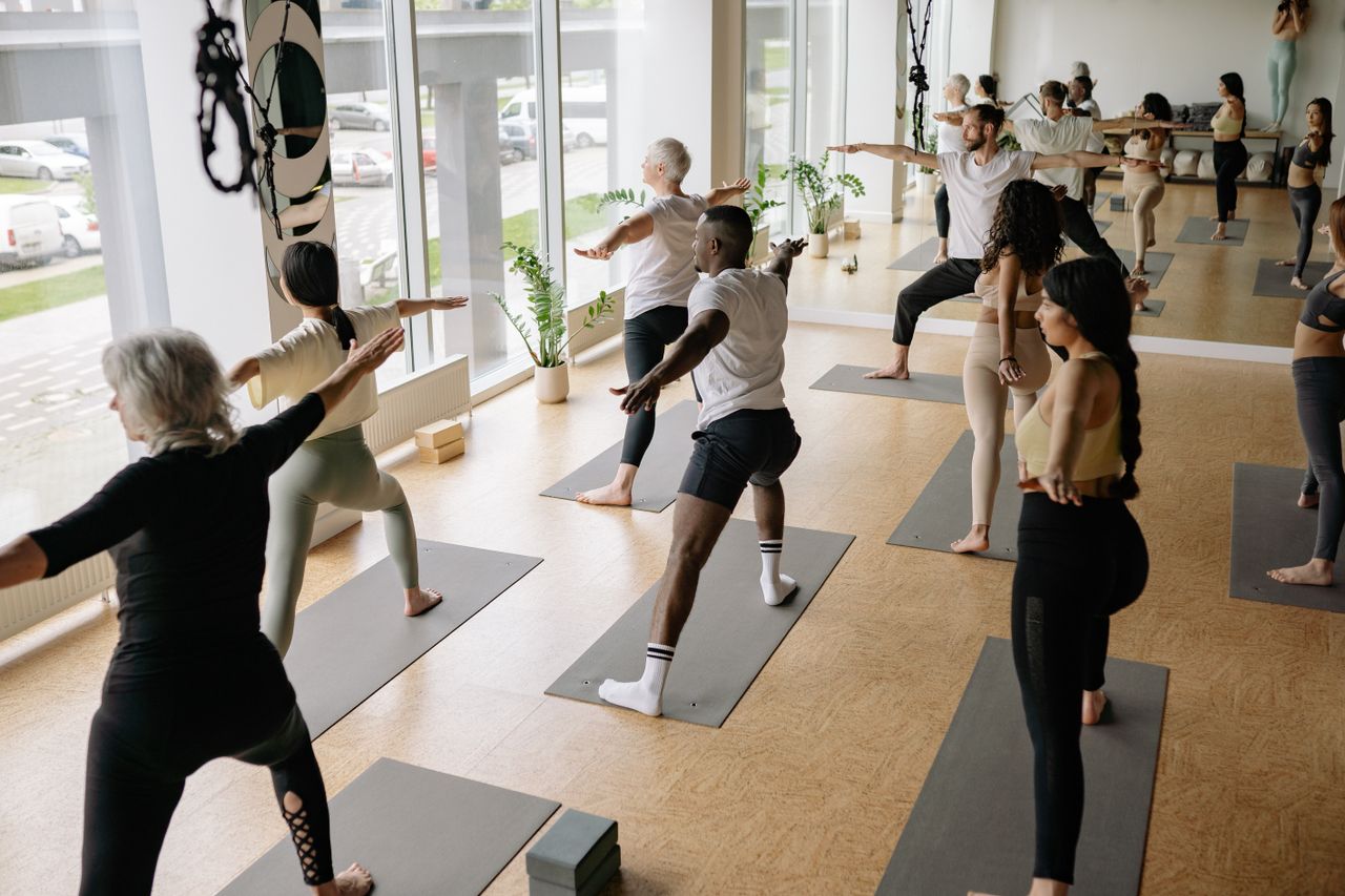 facilities A diverse group of adults practicing yoga indoors, promoting wellness and mindfulness.